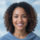 Portrait of a smiling woman in her late 20s, expressing satisfaction and trust against a soft blue and white background.