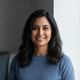Smiling South Asian woman in smart casual attire, exuding confidence and well-being in a headshot.